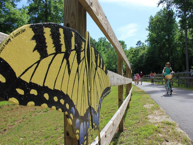 Clayton Riverwalk trail with cyclists and butterfly mural along greenway