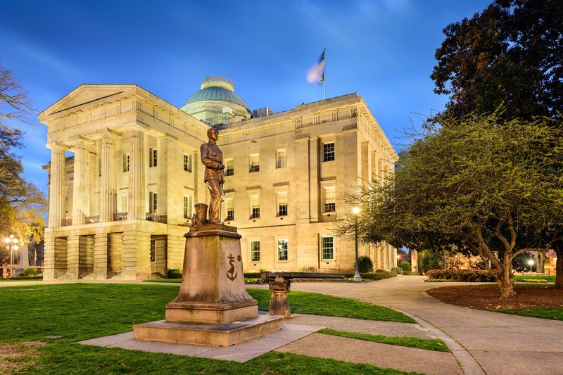 North Carolina State Capitol building with statue and landscaped grounds in Raleigh, North Carolina.