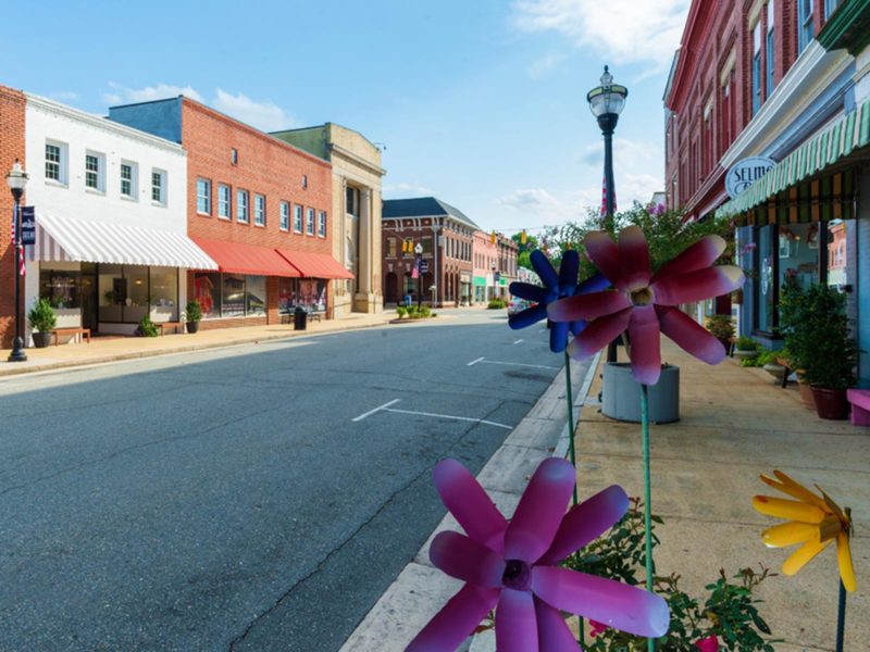 Downtown Selma streetscape with colorful buildings and decorative flowers along the sidewalk in Selma, North Carolina.